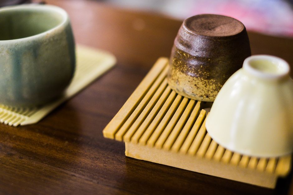 A close-up shot of ceramic tea cups on a wooden tray, highlighting traditional and earthy textures.
