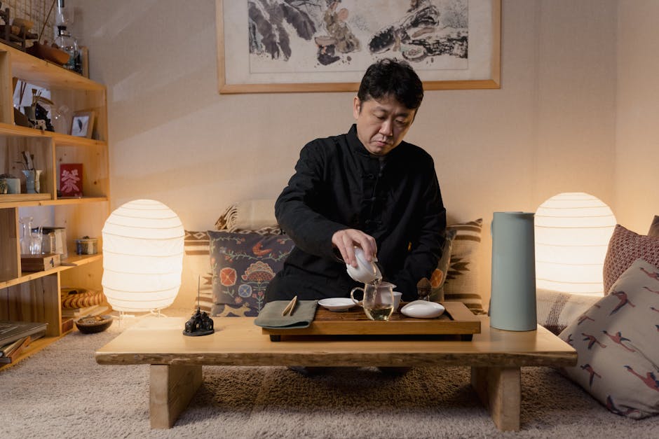 Man pouring tea in a traditional room with a wooden table and stylish decor.